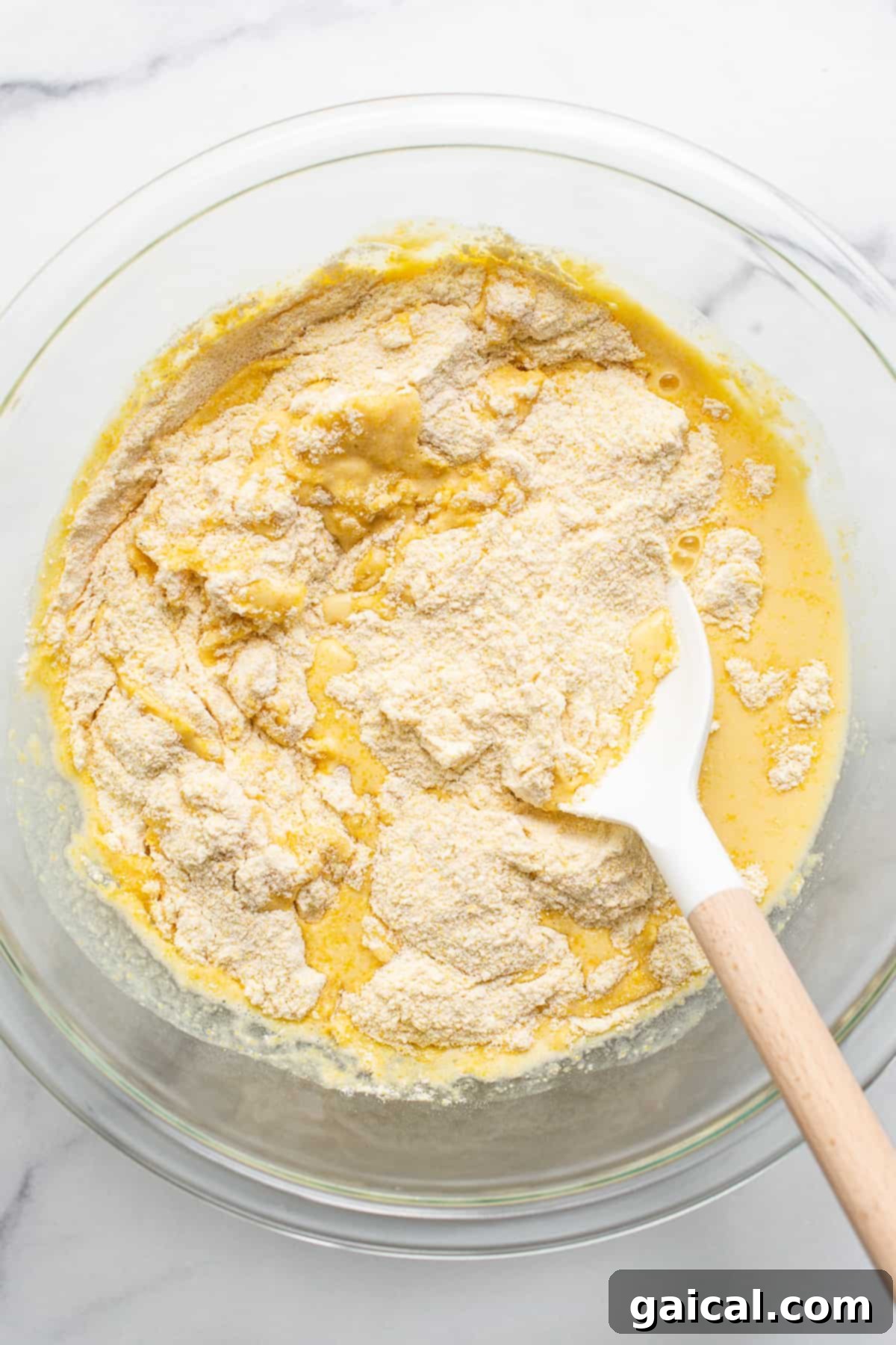 This jalapeño corn pudding recipe is made completely in a cast iron skillet in under an hand hour. It packs the perfect combo of sweet and spicy that you'll absolutely love! A large mixing bowl filled with a smooth, golden cornbread batter, ready for baking.