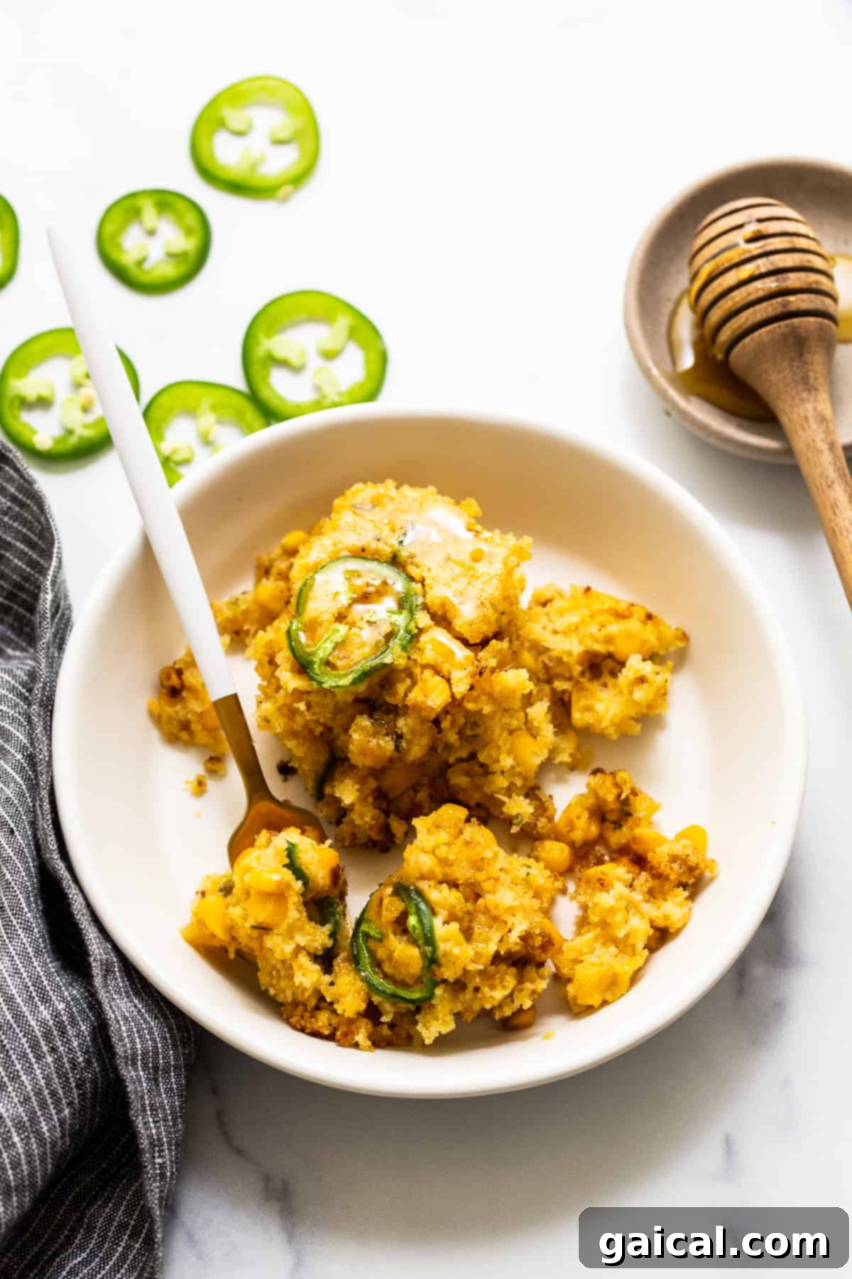 This jalapeño corn pudding recipe is made completely in a cast iron skillet in under an hour. It packs the perfect combo of sweet and spicy that you'll absolutely love! A bowl of creamy jalapeño corn pudding, perfectly portioned and ready to be enjoyed with a fork.