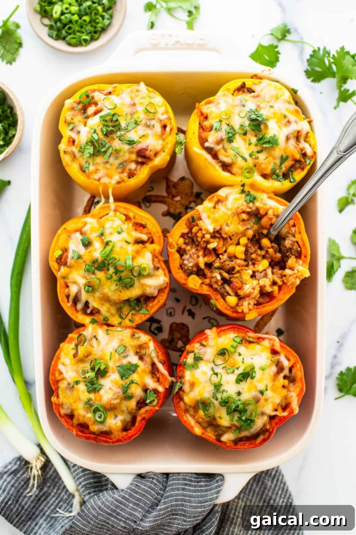 Easy stuffed peppers in a casserole dish topped with shredded cheese and fresh herbs.
