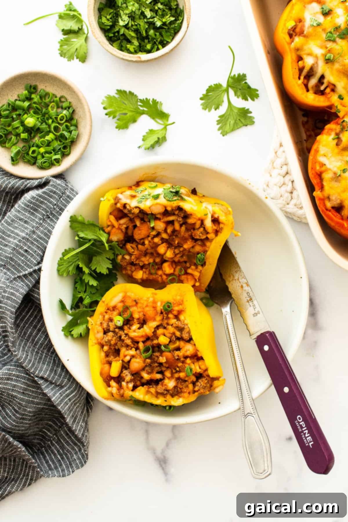 A perfectly cooked stuffed pepper, cut in half on a white plate, showcasing its hearty, cheesy filling.