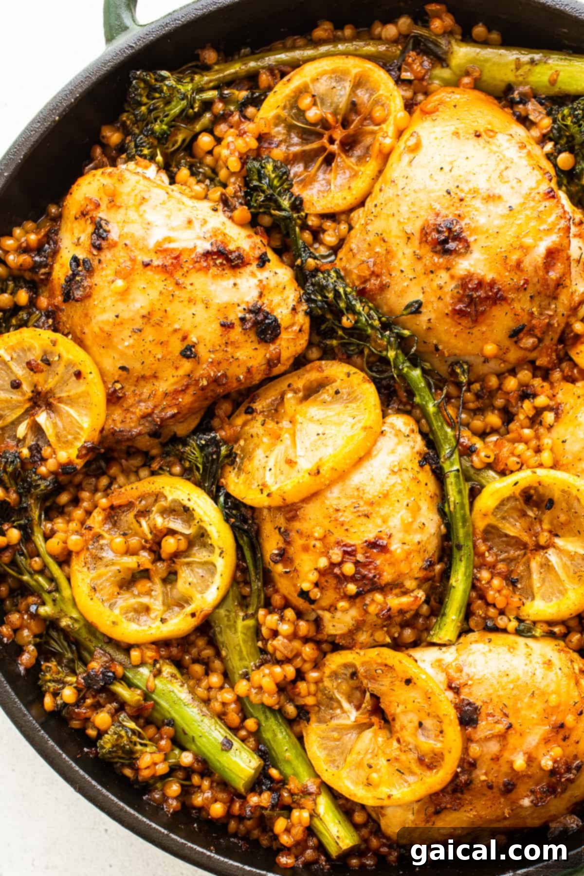 Baked Lemon Chicken Skillet A vibrant lemon chicken skillet, freshly baked, with tender chicken, couscous, and broccolini, garnished and ready to serve.