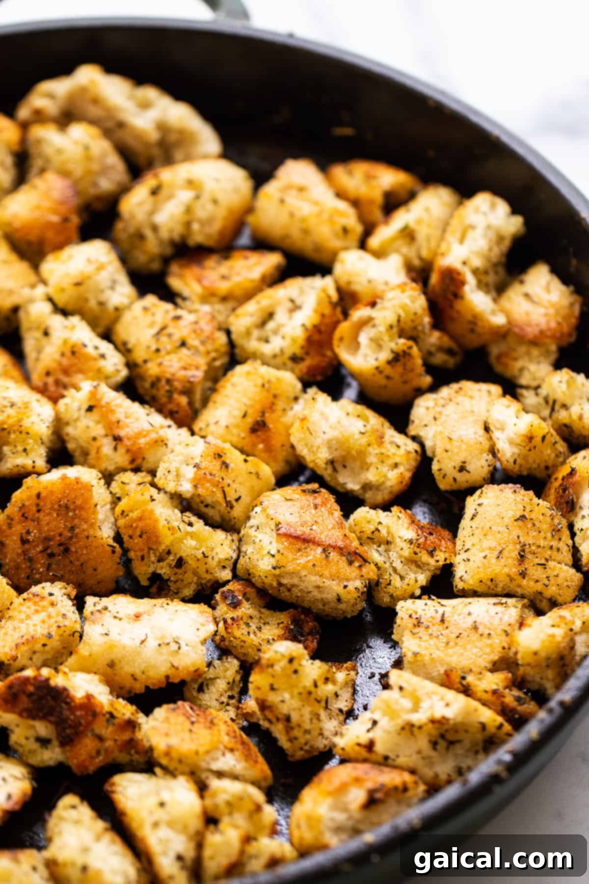 Perfectly Seasoned Pan-Fried Homemade Croutons Golden brown homemade croutons in a cast iron skillet, ready to be served on a salad or soup.