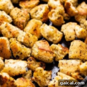 A square image of crispy homemade croutons in a cast iron pan, ready to be served.