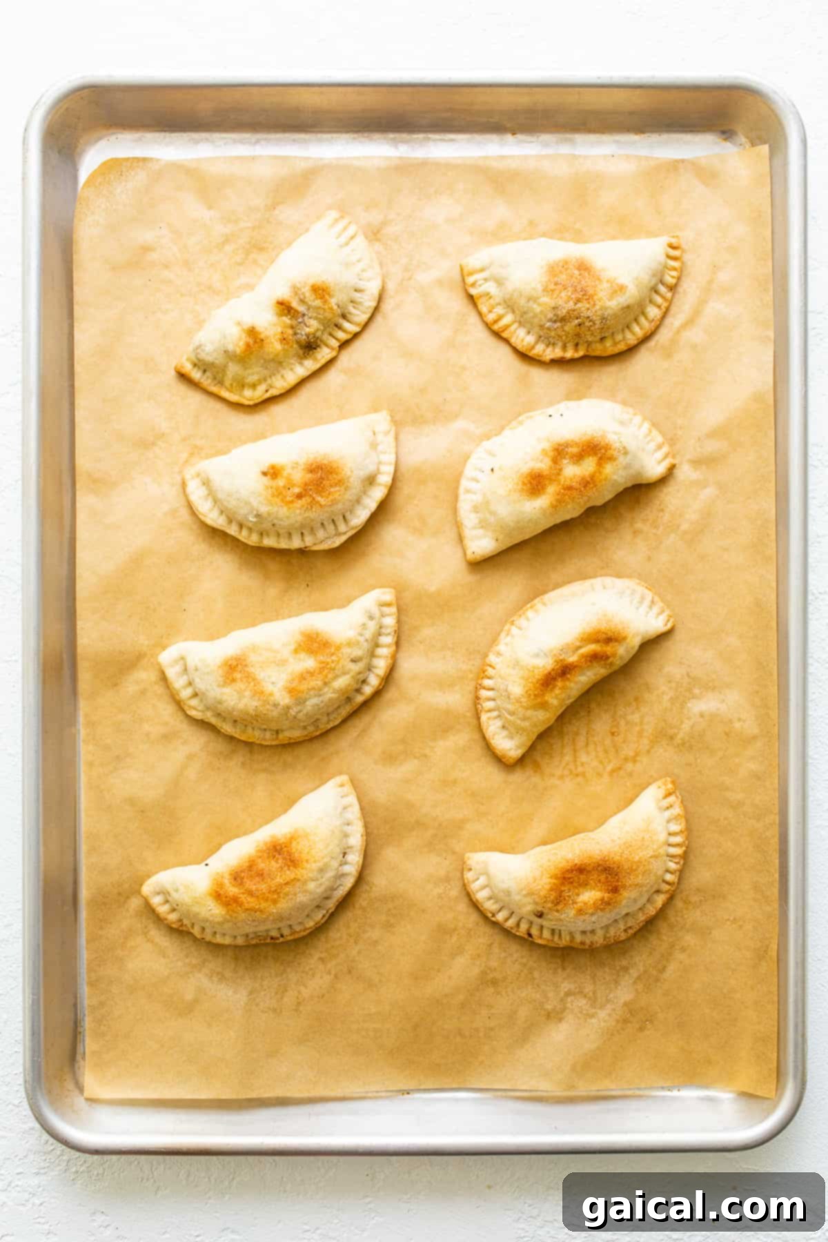 Savory Beef and Sweet Potato Empanadas 8 A selection of baked sweet potato ground beef empanadas on a rustic wooden board, ready to serve.