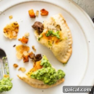 Sweet Potato Ground Beef Empanadas served on a plate with green sauce drizzled over them.