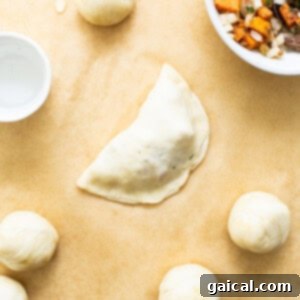 Savory Beef and Sweet Potato Empanadas 16 Assembled empanadas laid out on parchment paper before cooking.
