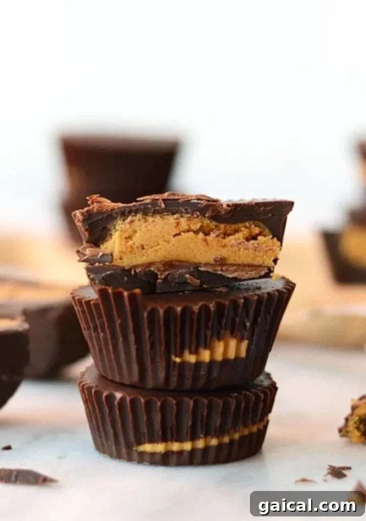 Delicious Protein Peanut Butter Cups with a high-protein twist A stack of homemade protein peanut butter cups, featuring rich dark chocolate shells and a creamy peanut butter protein filling, set against a light background.