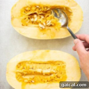 Spaghetti squash halves on a baking sheet before roasting.