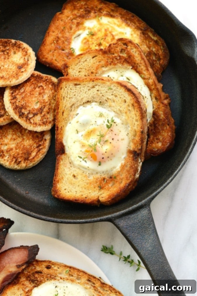 Eggs in a Basket (AKA Egg in a Hole) is such a fun twist on breakfast. Crack your egg right into a piece of toast for an open-face breakfast sandwich! Egg in a frame cooking in a cast iron pan, showing the egg sizzling within the toast