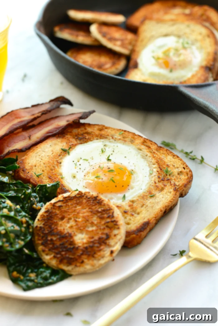 Eggs in a Basket (AKA Egg in a Hole) is such a fun twist on breakfast. Crack your egg right into a piece of toast for an open-face breakfast sandwich! Egg in a hole on a plate, served with crispy bacon strips on the side