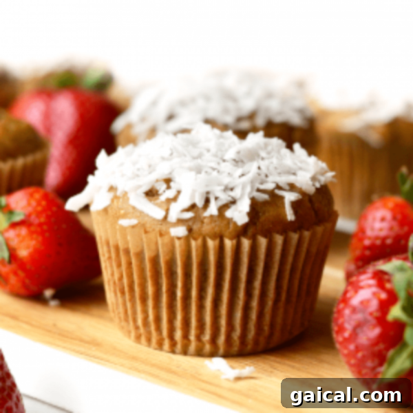 A tray of muffins with strawberries and coconut flakes topping.