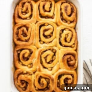 Baked cinnamon rolls in a white baking dish.