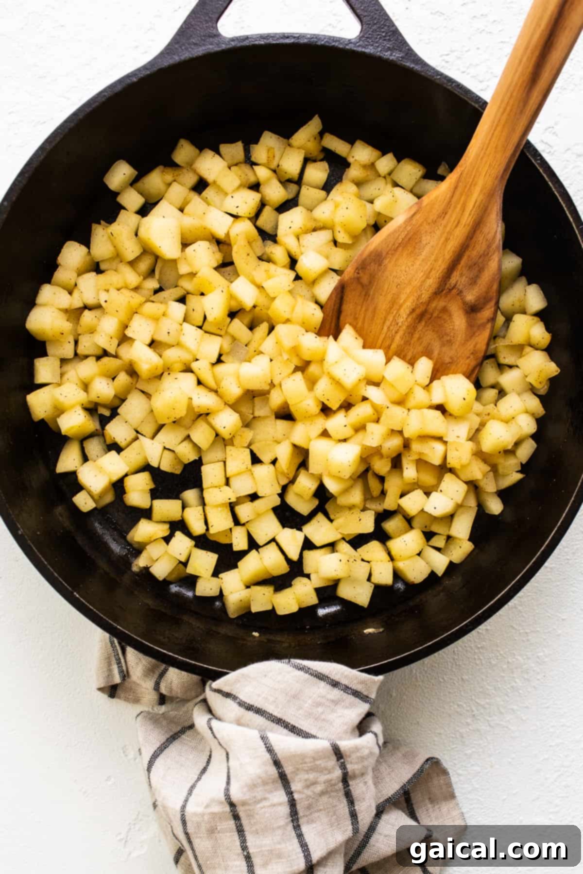 Honey crisp apples sauteing in a cast iron skillet, emitting a delicious aroma.