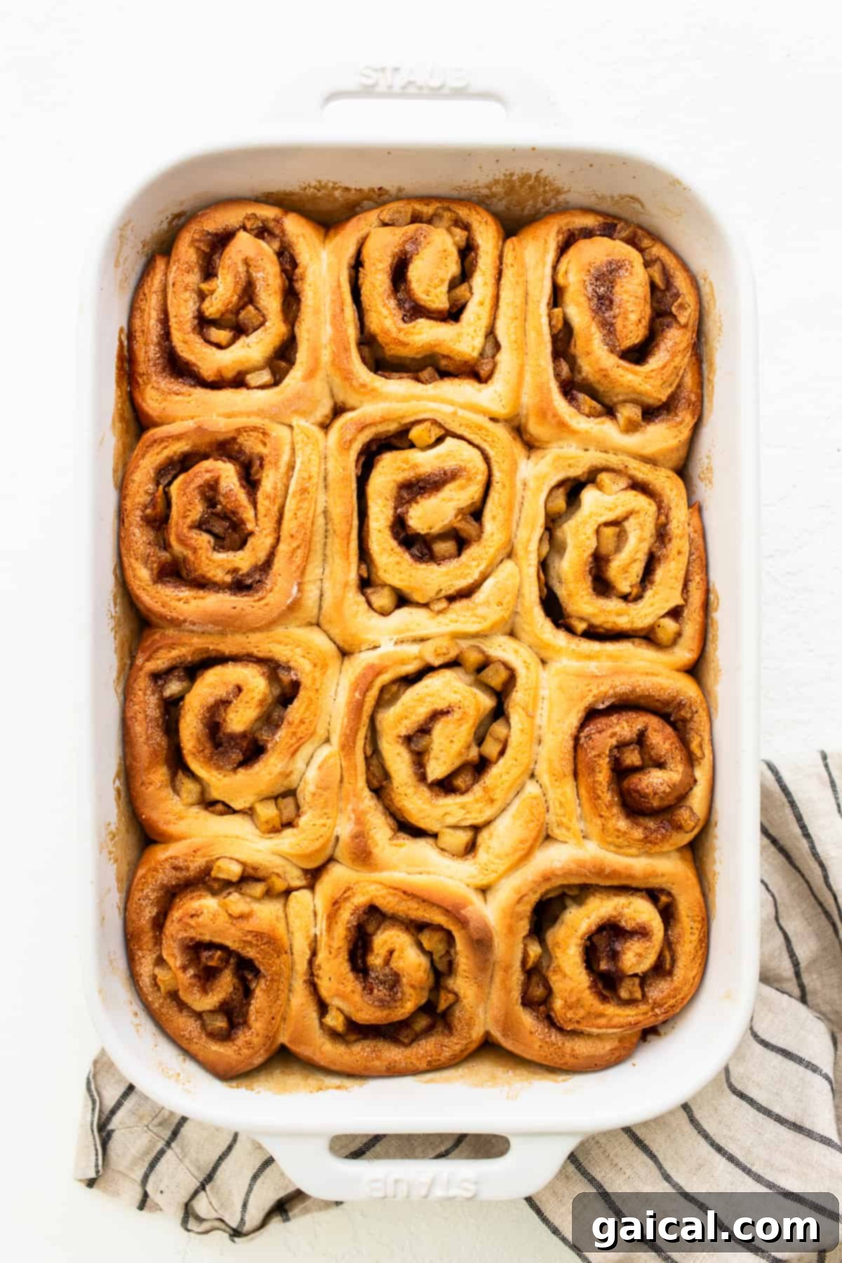 Apple cinnamon rolls fresh out of the oven in a casserole dish, perfectly golden brown.