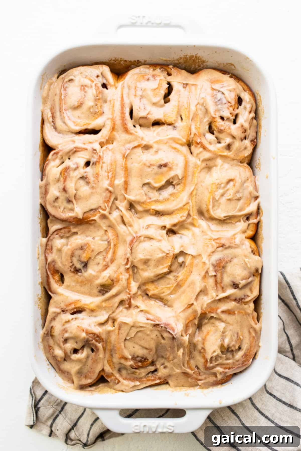 Apple cinnamon rolls completely covered in luscious brown butter cream cheese frosting, ready to be enjoyed.