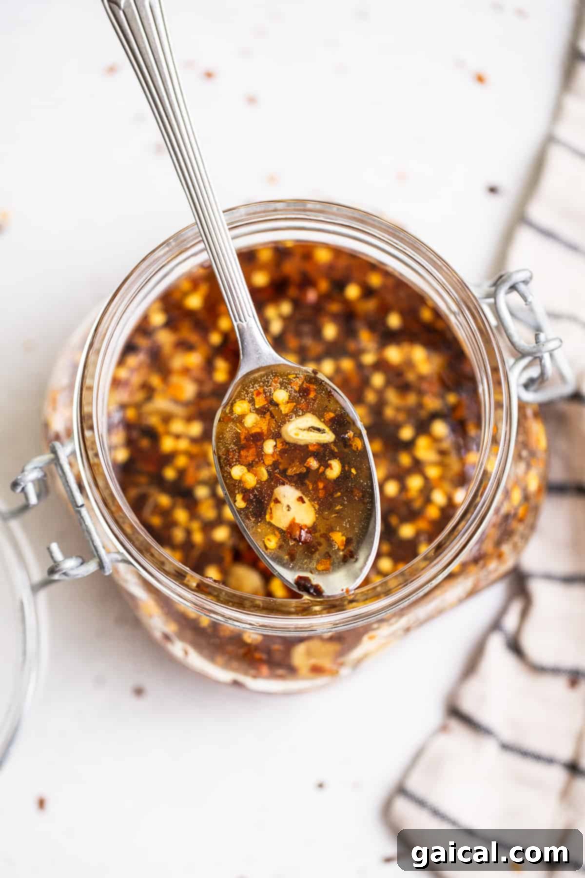 Our 4-ingredient hot honey sauce is hot, sticky and a little sweet. It's the perfect sauce to drizzle over chicken, seafood, pizza, roasted veggies and more! Hot honey on a spoon, showcasing its sticky, glossy texture.