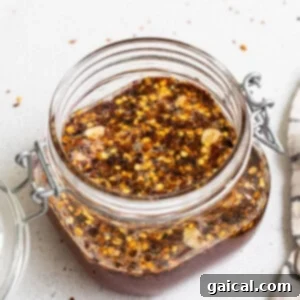A jar of hot honey chili sauce with a spoon.
