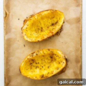 Two halves of baked spaghetti squash on a baking sheet, golden and tender, ready for the next step.