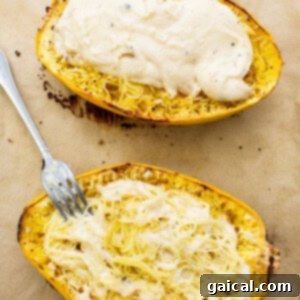 Two squash boats with a fork on top, after being generously coated with creamy cheese sauce.