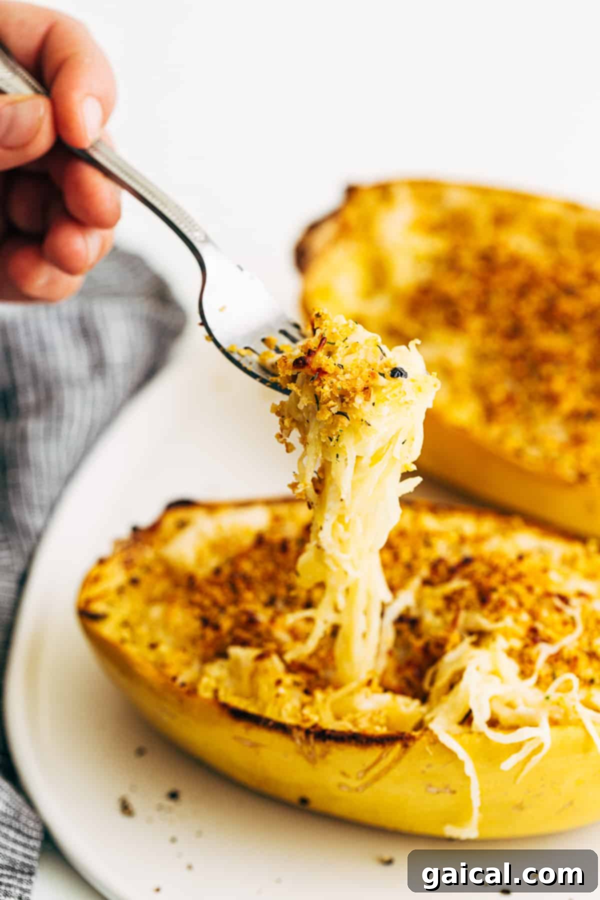 A fork lifting a delicious bite of creamy Spaghetti Squash Mac and Cheese, showcasing the noodle-like squash strands.