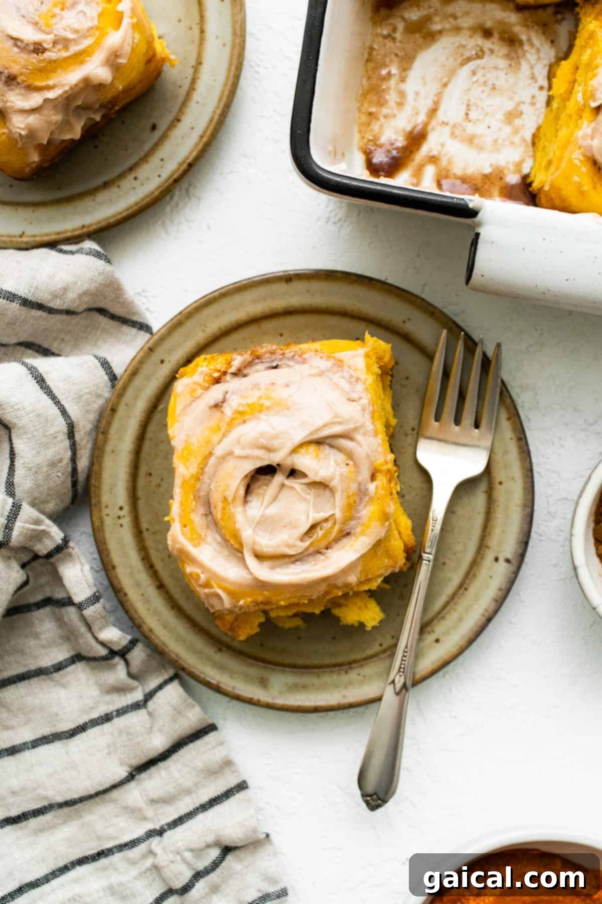 Enjoying a Pumpkin Cinnamon Roll A pumpkin cinnamon roll on a plate, with a fork poised to take a bite, highlighting its soft, gooey texture.