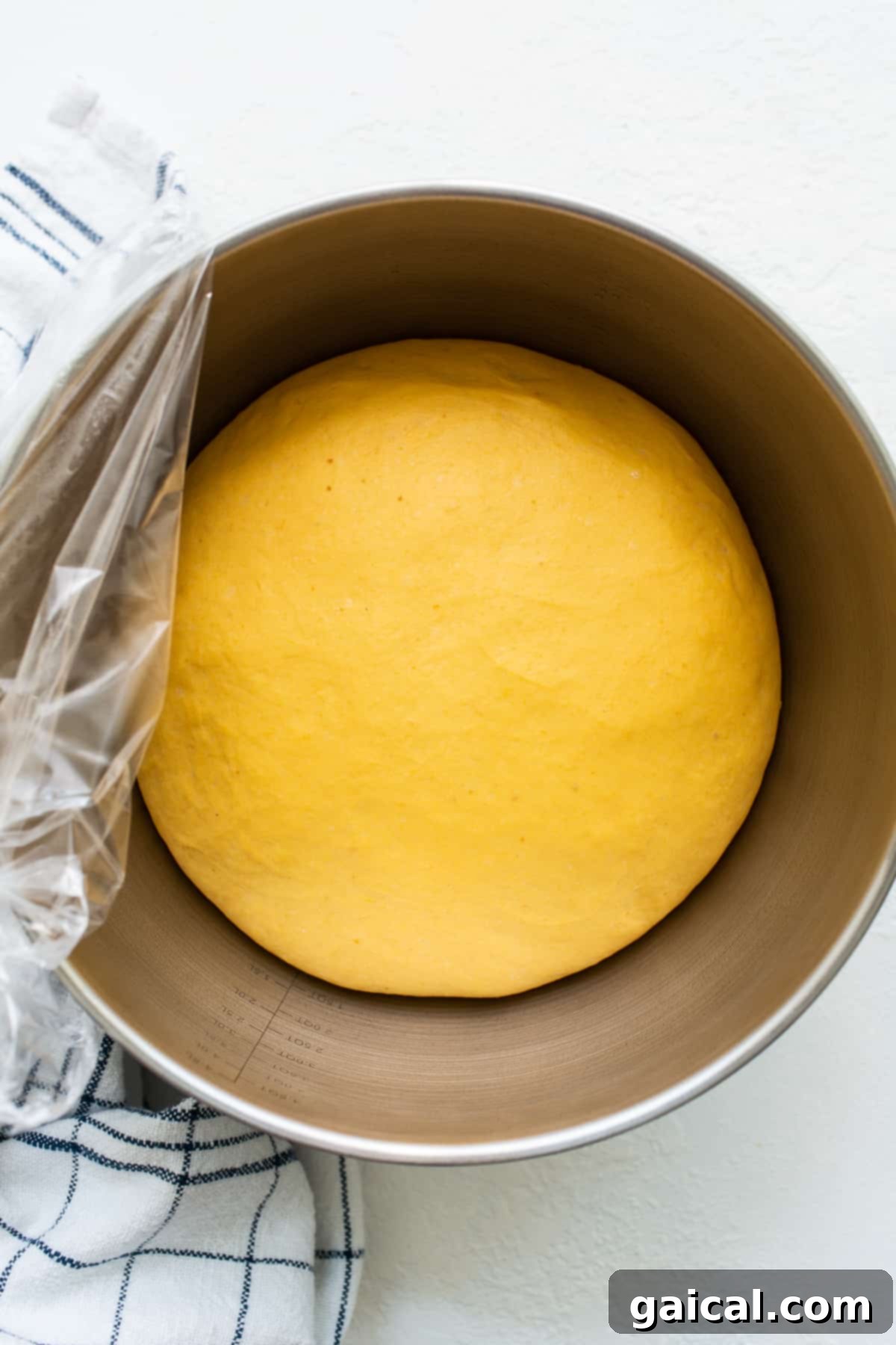 Pumpkin Cinnamon Roll Dough Rising Soft and elastic pumpkin cinnamon roll dough rising in a bowl, covered for warmth.
