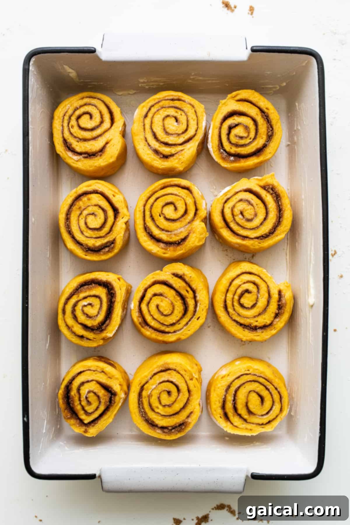 Warm Pumpkin Cinnamon Rolls in Baking Dish Freshly baked pumpkin cinnamon rolls still warm in a ceramic baking dish, ready for frosting.
