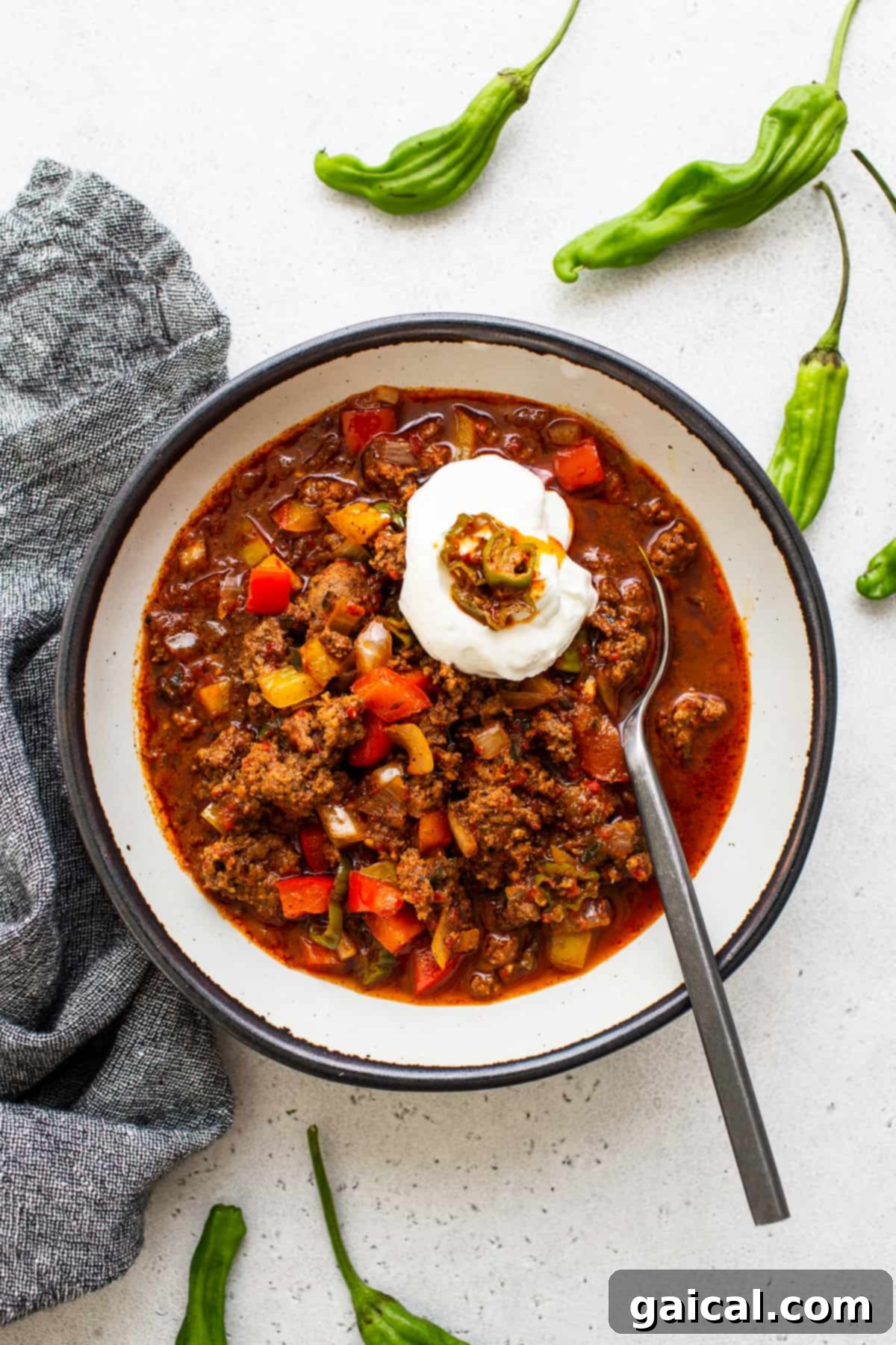 Hearty Texas Red 7 A beautifully presented bowl of Texas chili, garnished with a swirl of cool sour cream and a sprinkle of vibrant hatch chilis, inviting you to take a bite.
