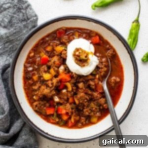 A vibrant bowl of Texas Chili, crowned with a swirl of sour cream, ready to be enjoyed.