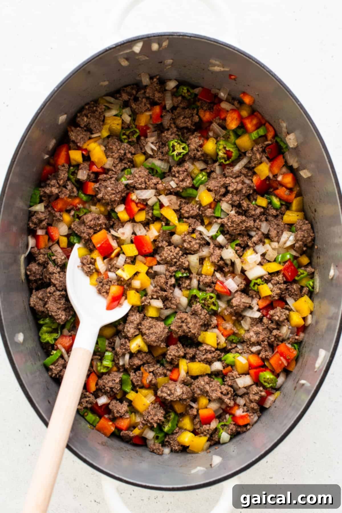 Hearty Texas Red 4 Sizzling ground beef, vibrant bell peppers, and fragrant onions cooking in a large Dutch oven, forming the hearty base of the chili.