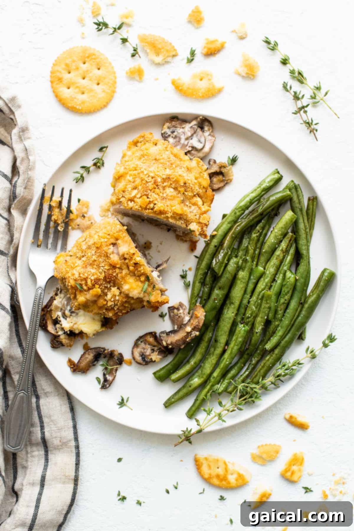 Gourmet Stuffed Pork Chop with Green Bean Side Dish A perfectly cooked, mushroom stuffed pork chop on a white plate, garnished with green beans.