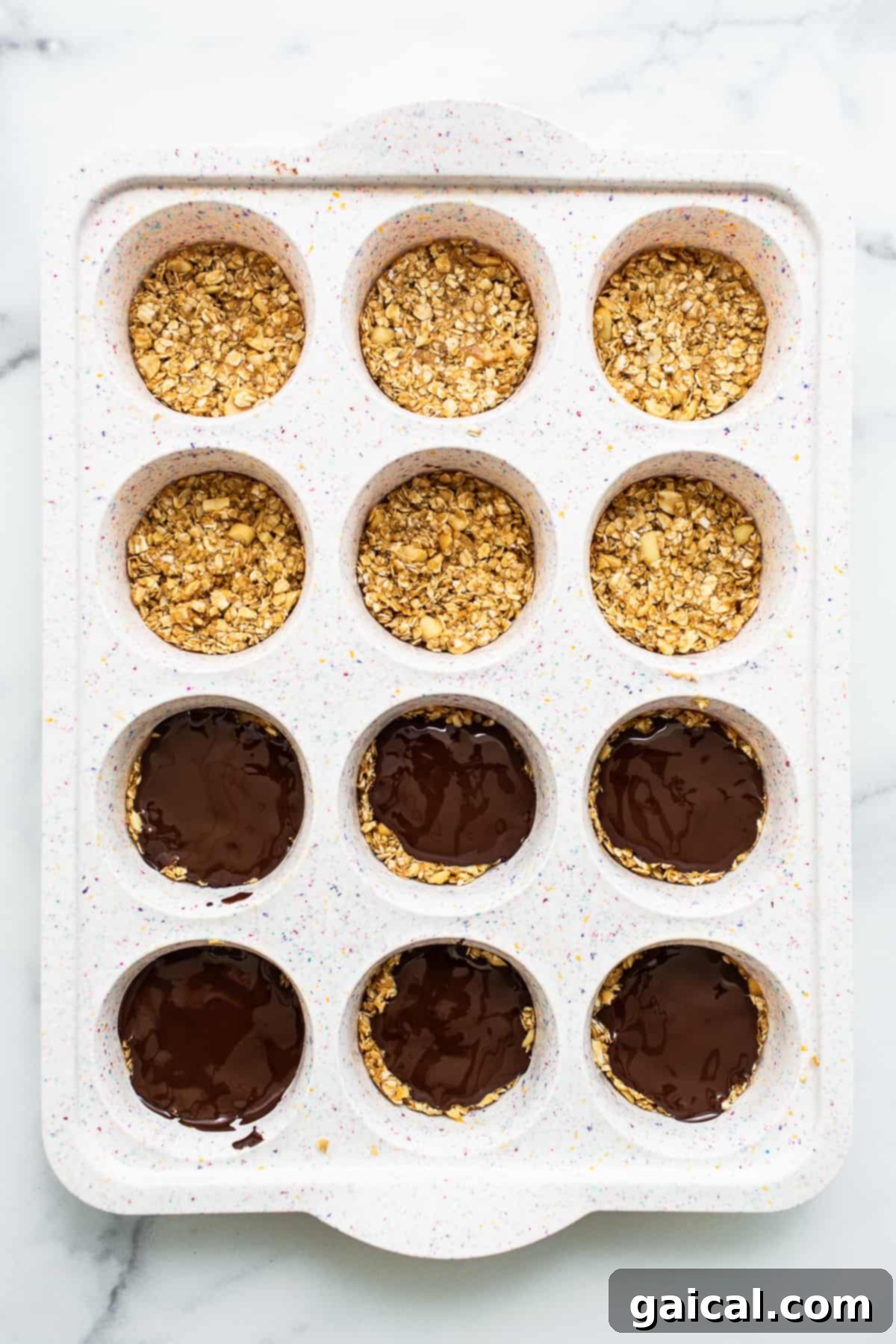 Peanut Butter Oat Cups in Muffin Tin No-bake peanut butter oat cups neatly arranged in a muffin tin, ready to be chilled.
