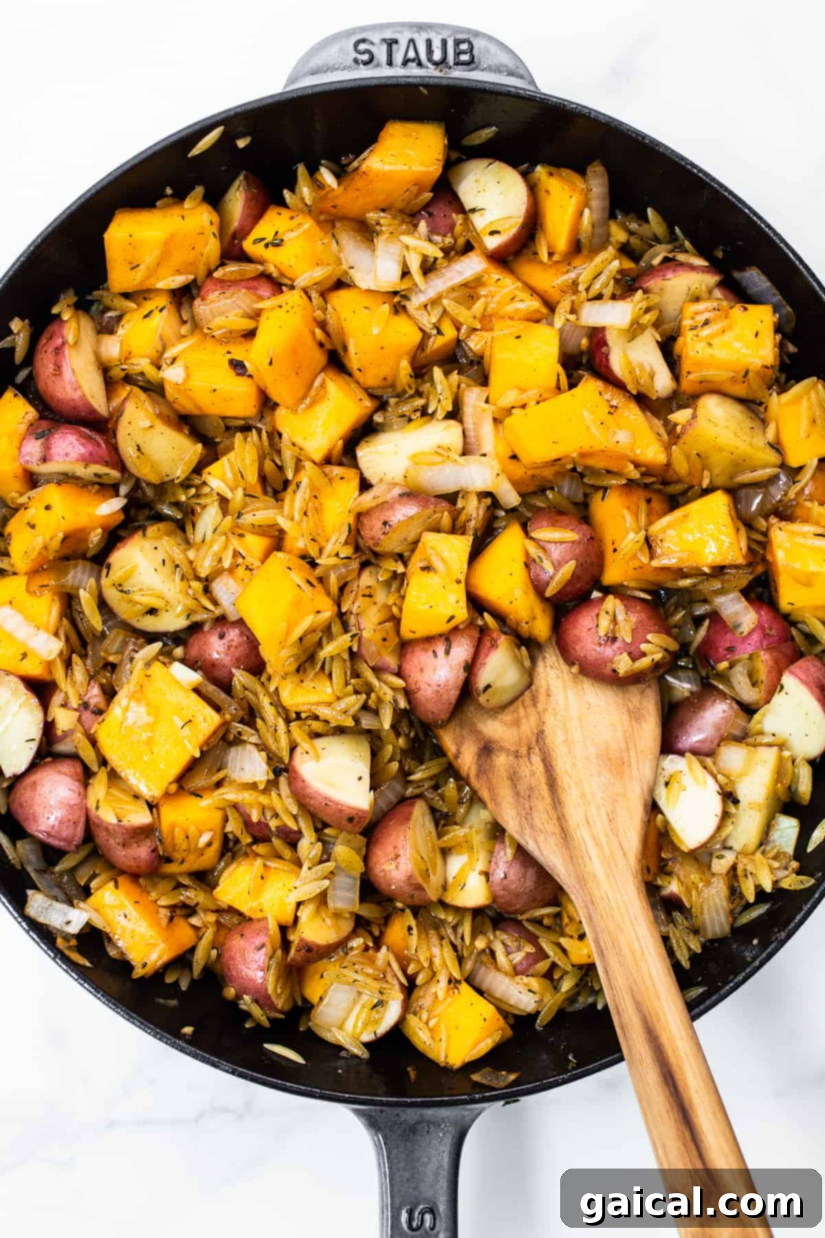 Golden Autumn Skillet Orzo 7 A beautiful arrangement of uncooked orzo pasta, diced butternut squash, and chopped red potatoes mingled together in a cast iron skillet, ready for cooking.