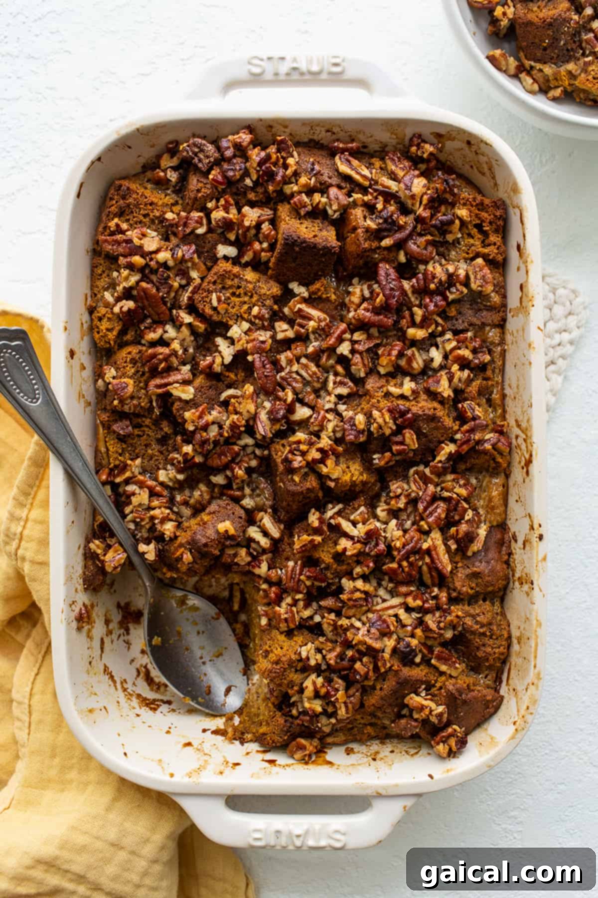 Delightful Pumpkin Bread Pudding for Fall Golden pumpkin bread pudding in a rustic casserole dish, generously portioned and ready to be served, topped with a crunchy pecan crust.