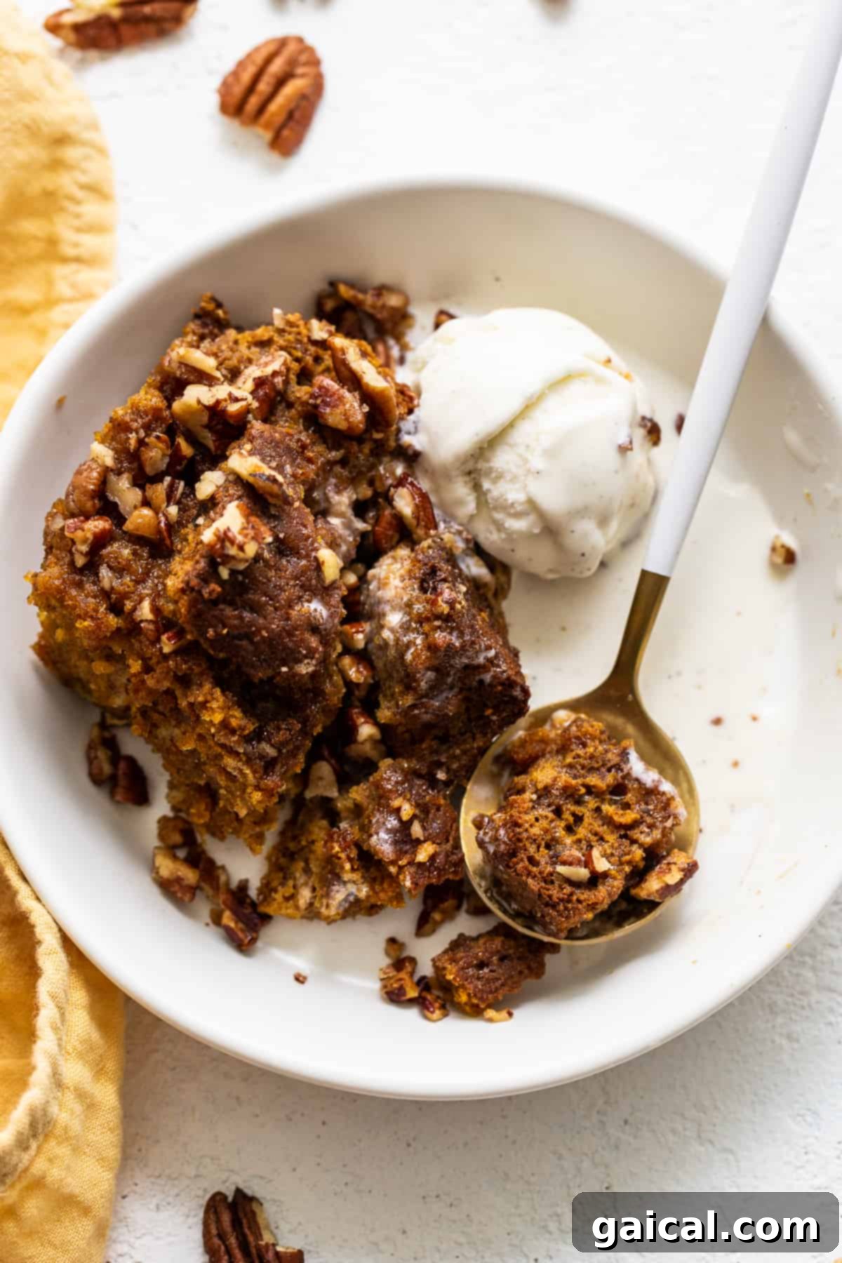 Pumpkin Bread Pudding Dessert A delectable bowl of pumpkin bread pudding served with a generous scoop of vanilla ice cream, garnished with a spoon, inviting a delightful taste.