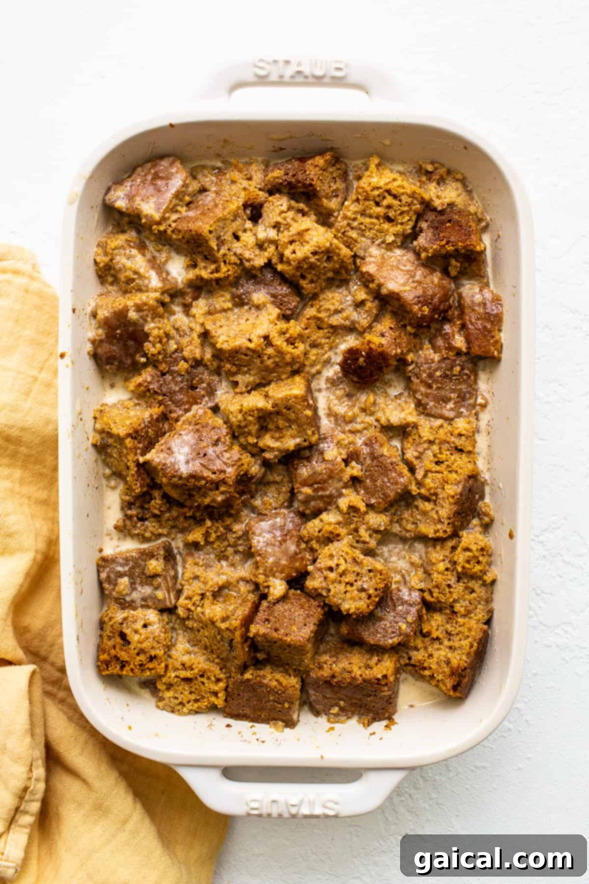Pumpkin Bread Pudding Pre-Bake Uncooked pumpkin bread pudding, perfectly assembled in a casserole dish, ready for the oven, showcasing the bread cubes and pecan topping.