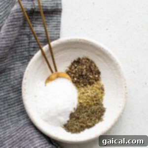 A white bowl with salt, pepper, and herbs.