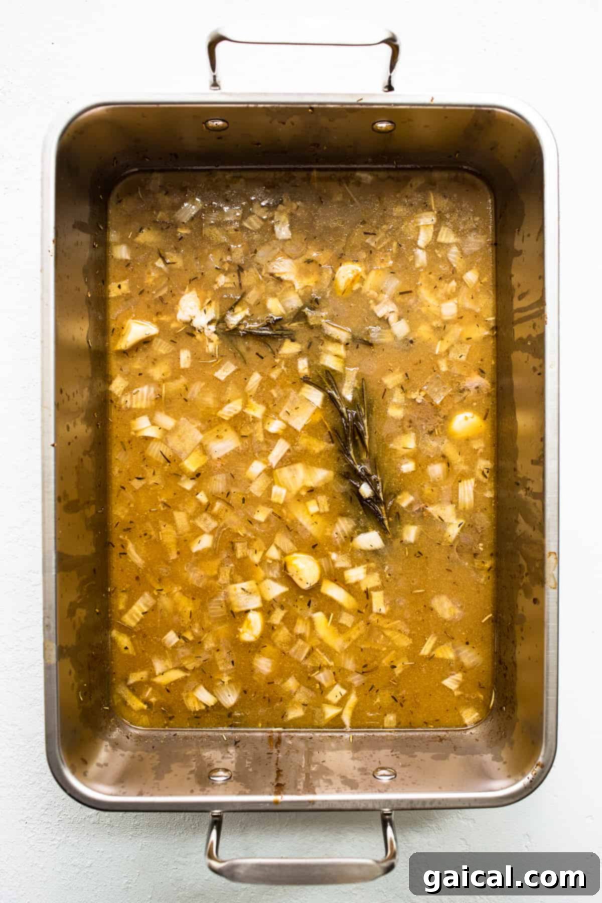 Turkey Drippings in Roasting Pan Close-up view of golden turkey drippings collected in the bottom of a roasting pan after cooking, ready for gravy making.
