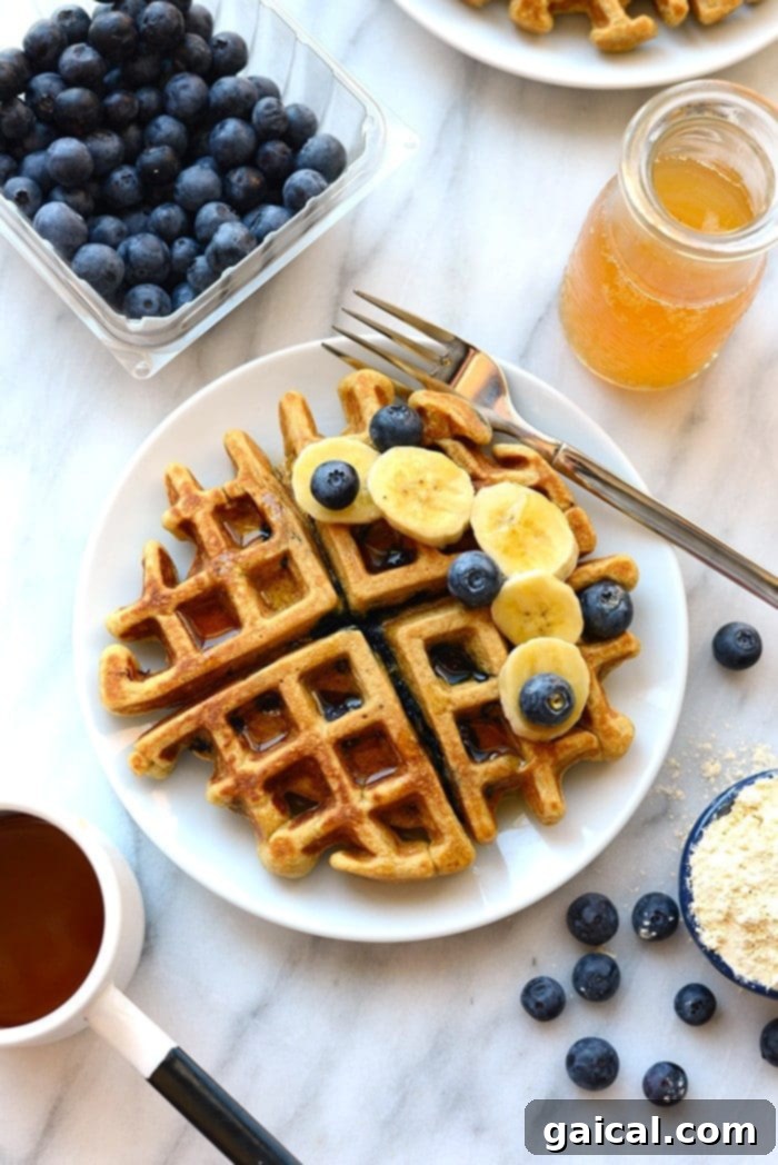 Wholesome Blueberry Waffles 6 A healthy waffle garnished with fresh blueberries and neatly sliced bananas on a pristine white plate.