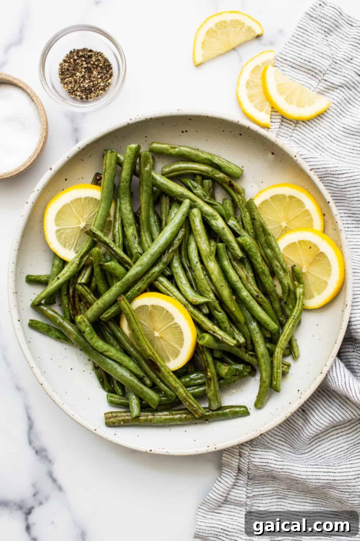 Garlic Parmesan Roasted Green Beans 2 Green beans in a serving bowl with lemon slices, ready to be enjoyed.