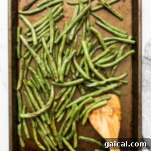 Freshly roasted green beans on a baking sheet, seasoned and ready to serve.