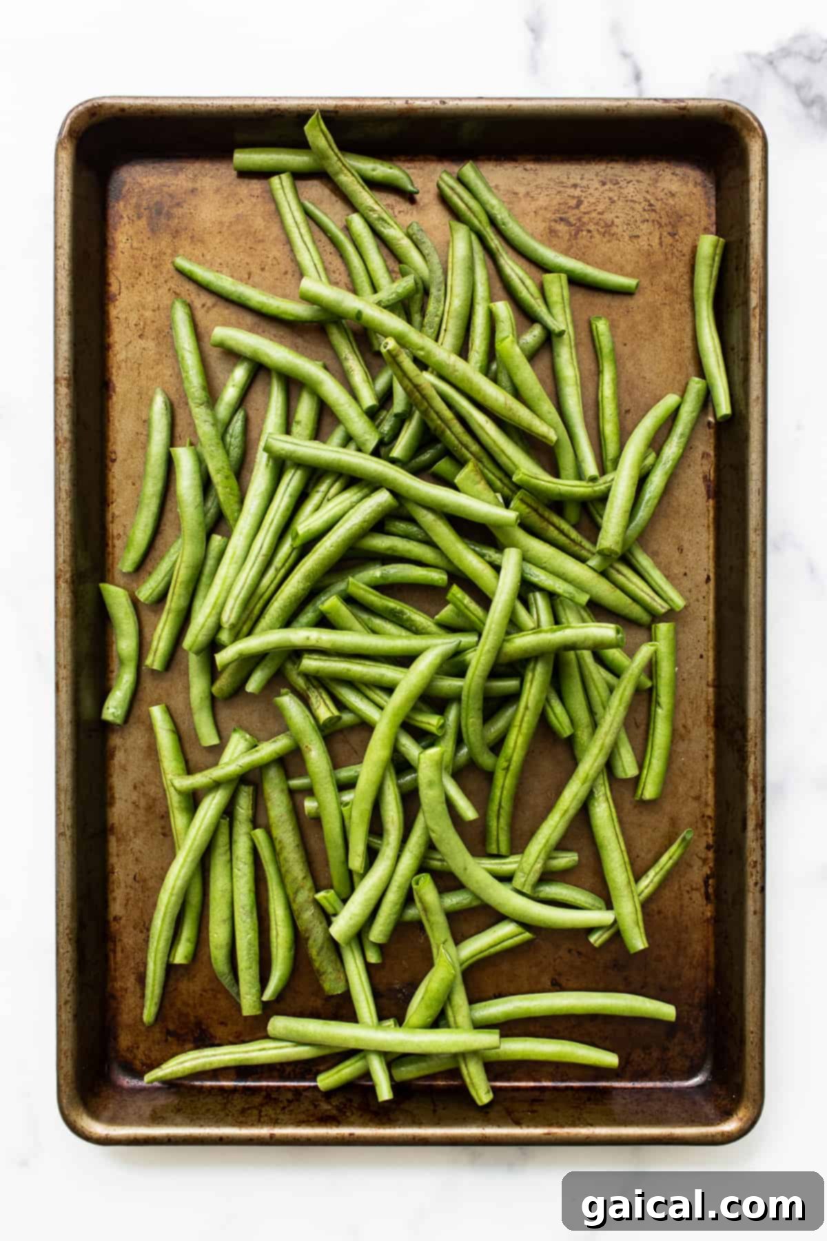 Garlic Parmesan Roasted Green Beans 3 Uncooked fresh green beans on a baking sheet, ready for seasoning.