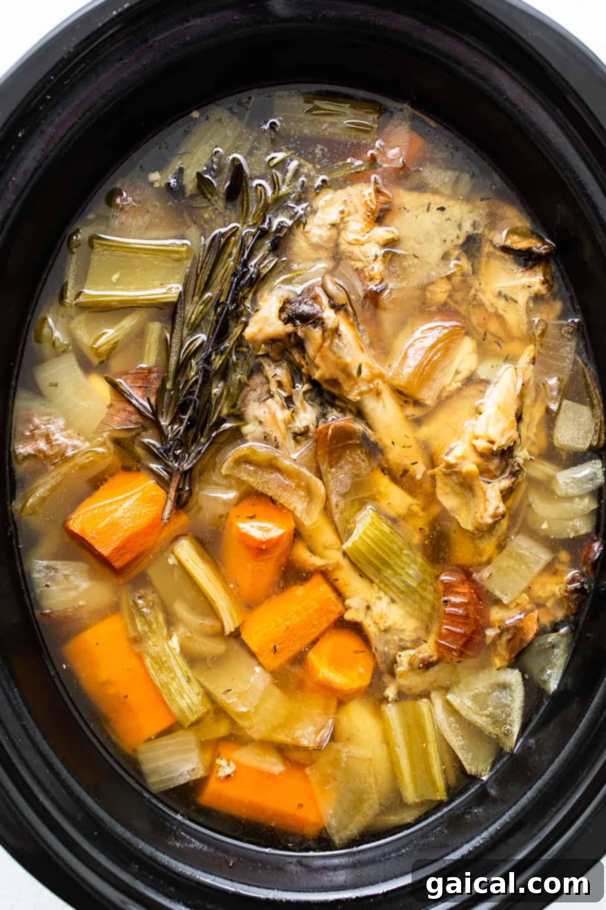 Slow Simmered Turkey Broth 8 Rich, golden turkey stock in a slow cooker, after hours of simmering, ready to be strained.