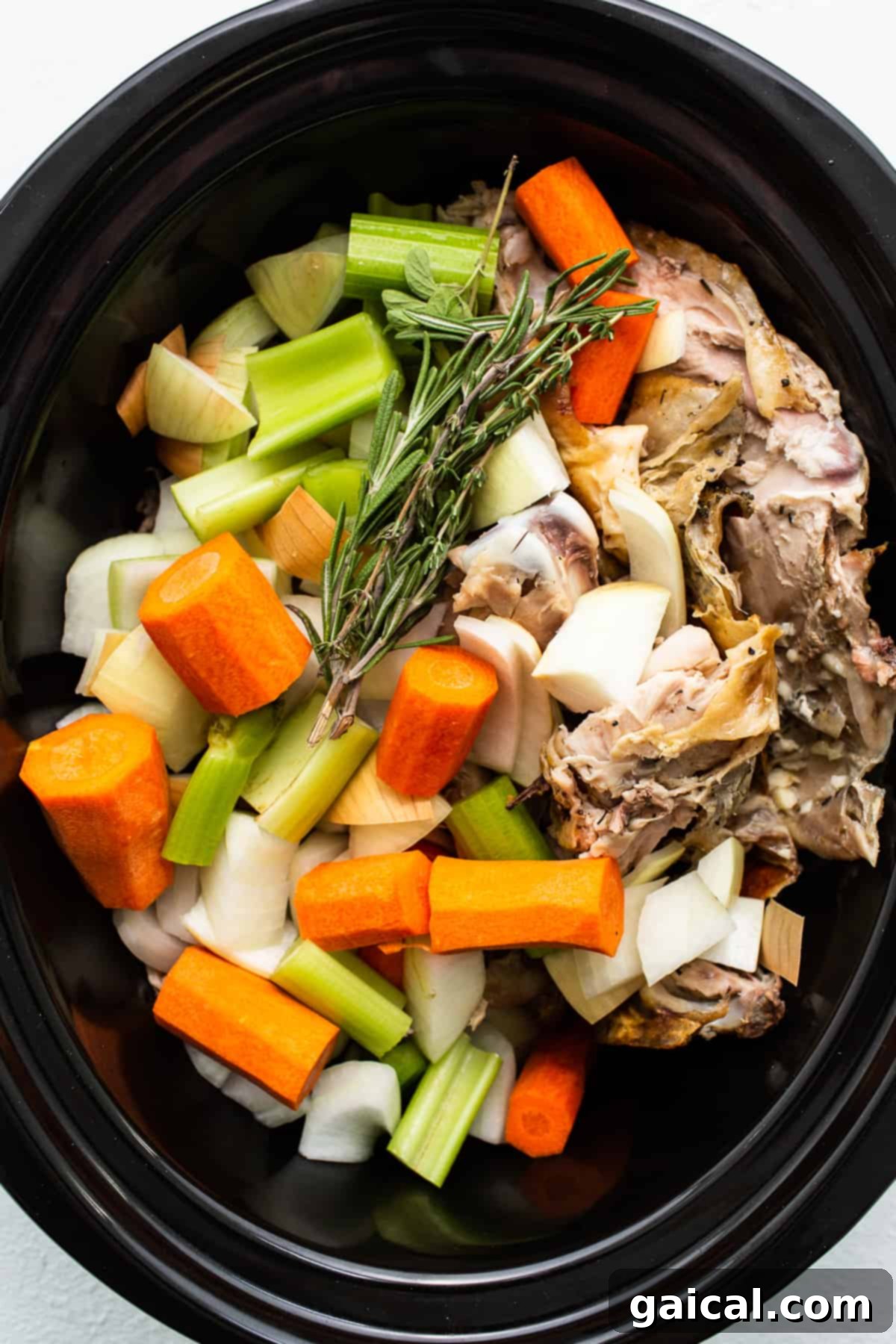 Slow Simmered Turkey Broth 4 Turkey carcass, carrots, celery, onion, garlic, and fresh herbs arranged in a slow cooker before adding water.