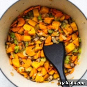 Hearty Turkey Wild Rice Soup 4 A pot filled with vegetables and turkey wild rice soup, alongside a black spatula.