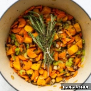 Hearty Turkey Wild Rice Soup 5 A pot filled with turkey, wild rice soup and sprigs of rosemary.