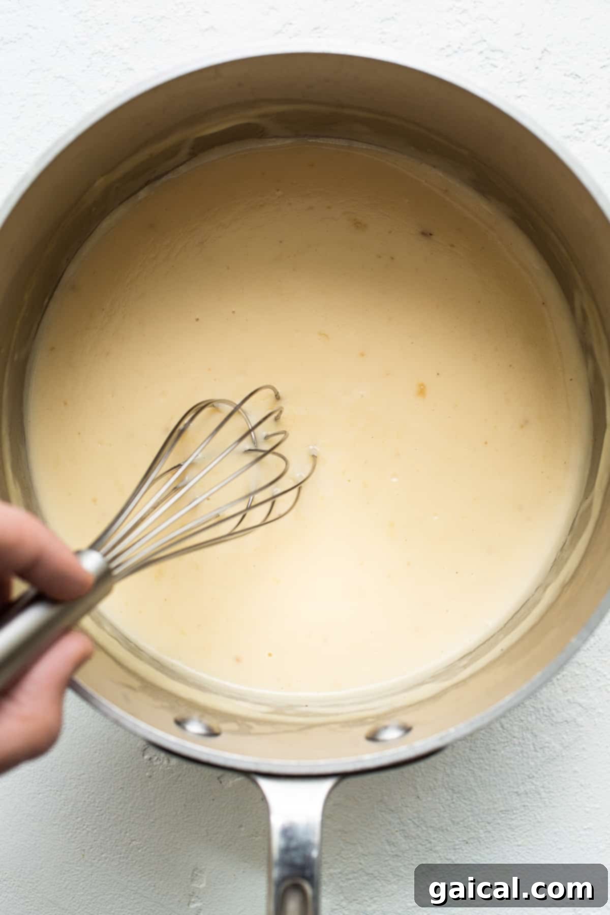 A golden-brown roux being whisked in a saucepan, the base for a creamy sauce.