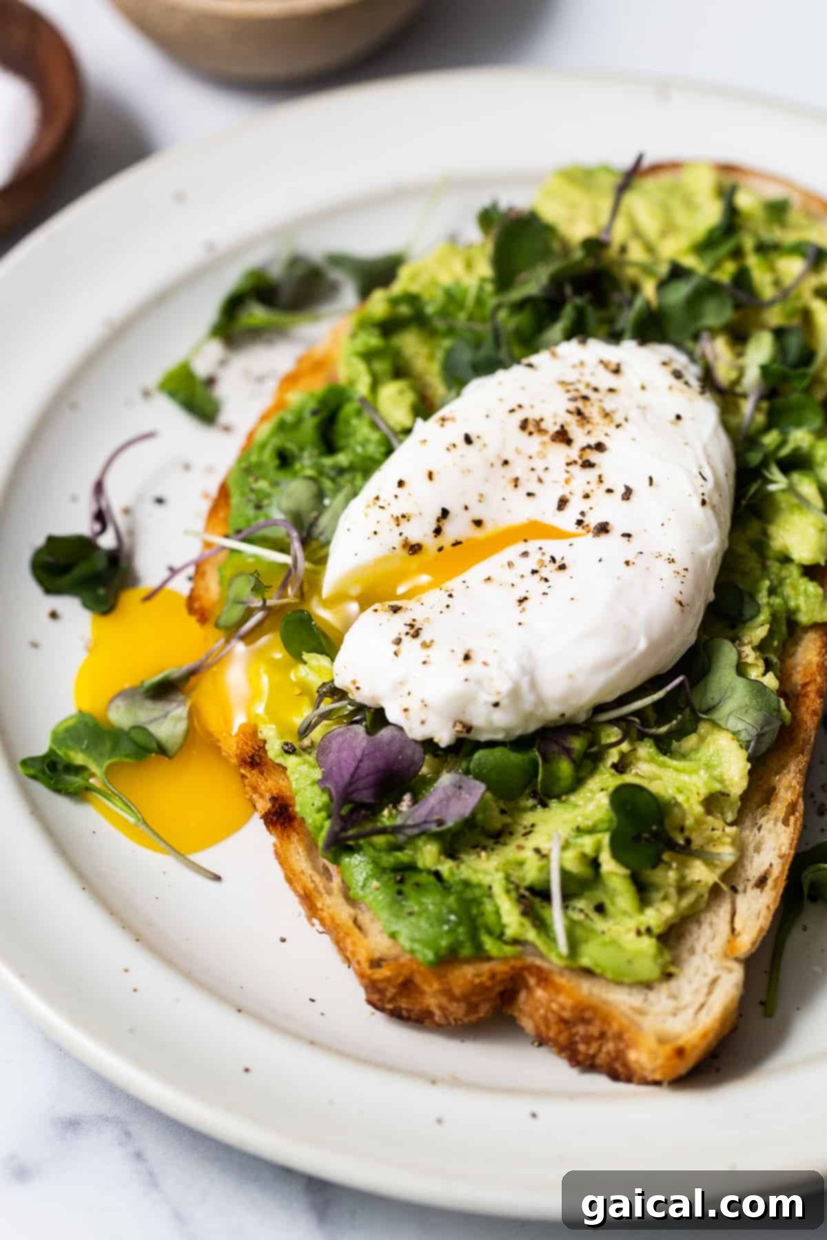 Poached egg on avocado toast – a healthy and delicious breakfast pairing. A perfectly poached egg resting on avocado toast, garnished with microgreens.