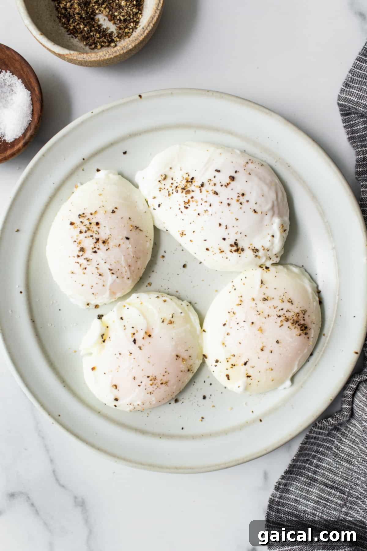 A plate of perfectly poached eggs, ready for your favorite breakfast. Four perfectly poached eggs neatly arranged on a white plate, ready to be served.