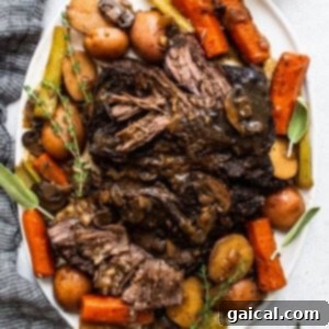 A hearty portion of pot roast served on a plate, featuring tender beef, carrots, and potatoes, topped with a rich gravy.